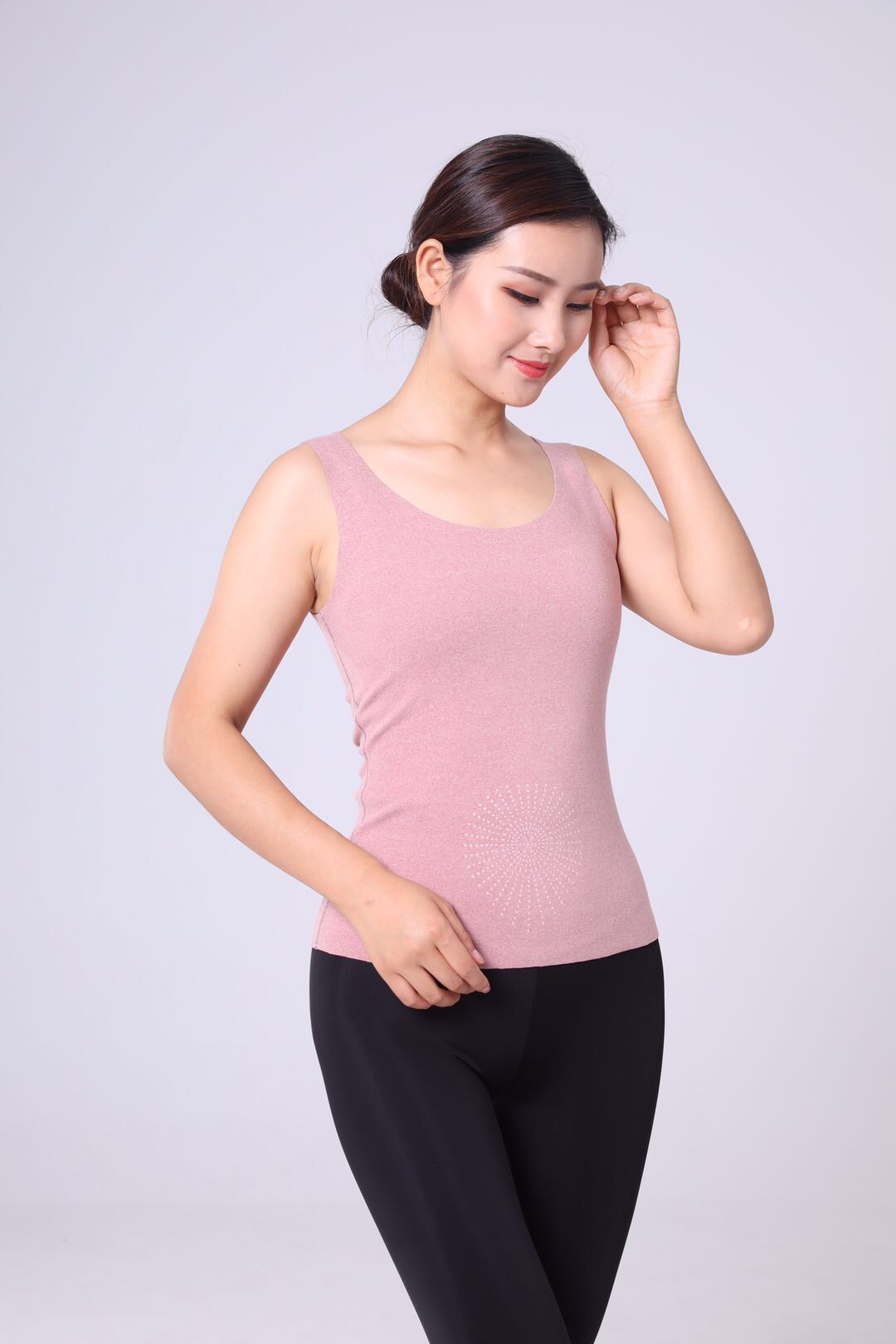 Woman wearing soft thermal base layer in neutral tone, standing by a window in early morning light