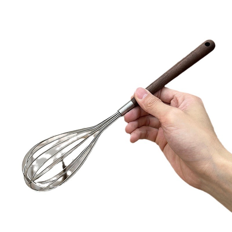 Set of whisks on wooden board with baking ingredients