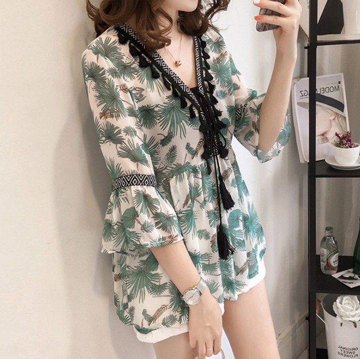 A loose floral chiffon shirt that covers the belly and cinches the waist, exuding an ethereal charm. It is a V-neck top with three-quarter sleeves