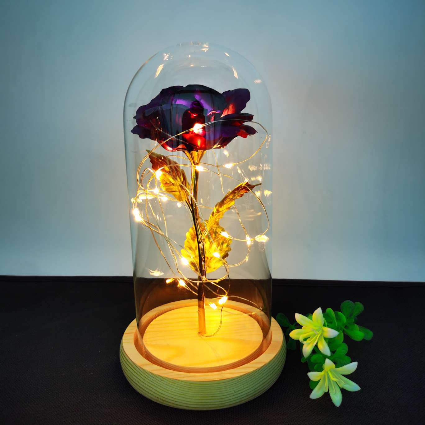 A decorative item with a glass cover and a solid wood base, featuring golden rose petals undefined