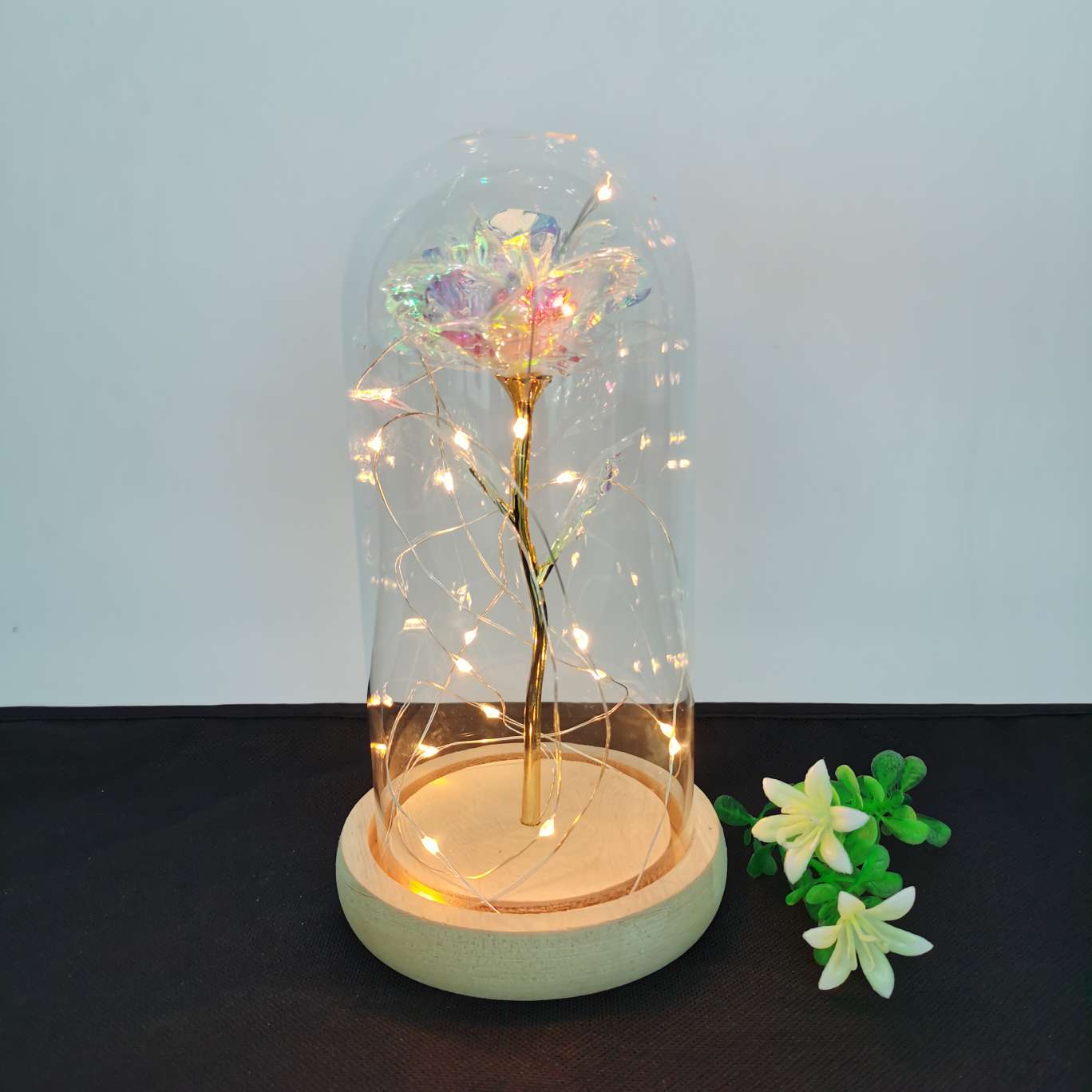 A decorative item with a glass cover and a solid wood base, featuring golden rose petals undefined