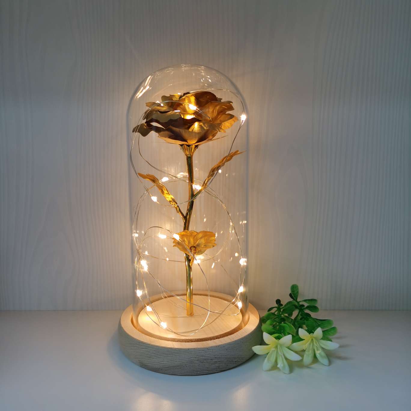 A decorative item with a glass cover and a solid wood base, featuring golden rose petals undefined