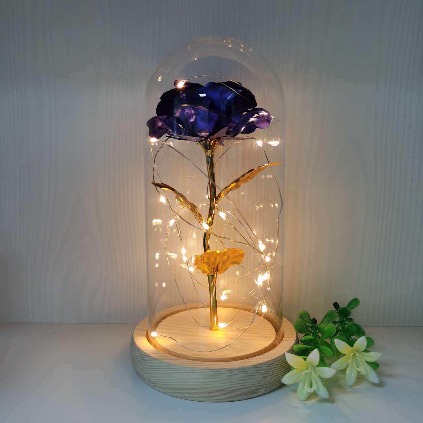 A decorative item with a glass cover and a solid wood base, featuring golden rose petals undefined