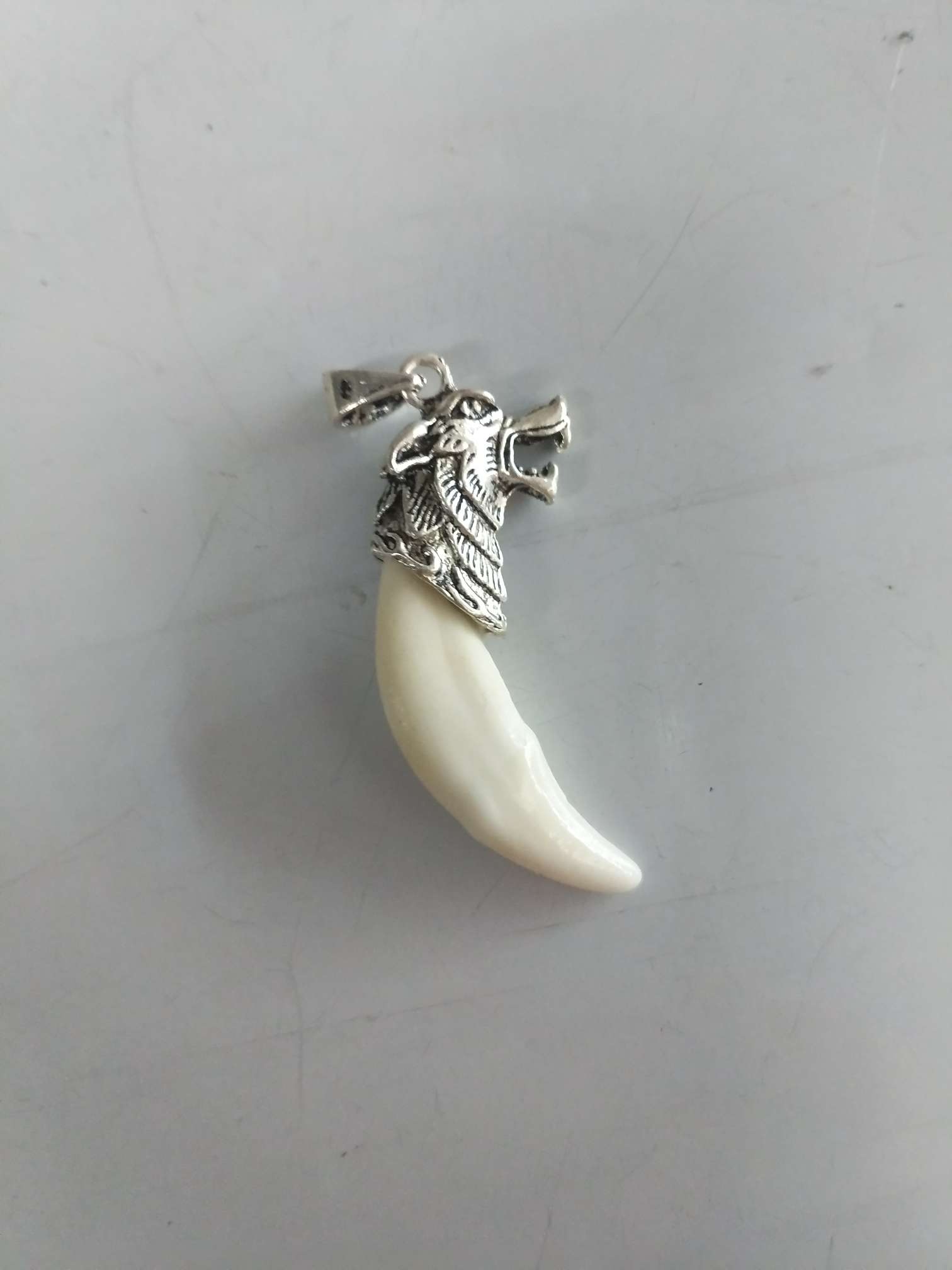 Wolf says a small white dog pendant necklace with inlaid braces is a really black dog tooth ornament. thumbnail