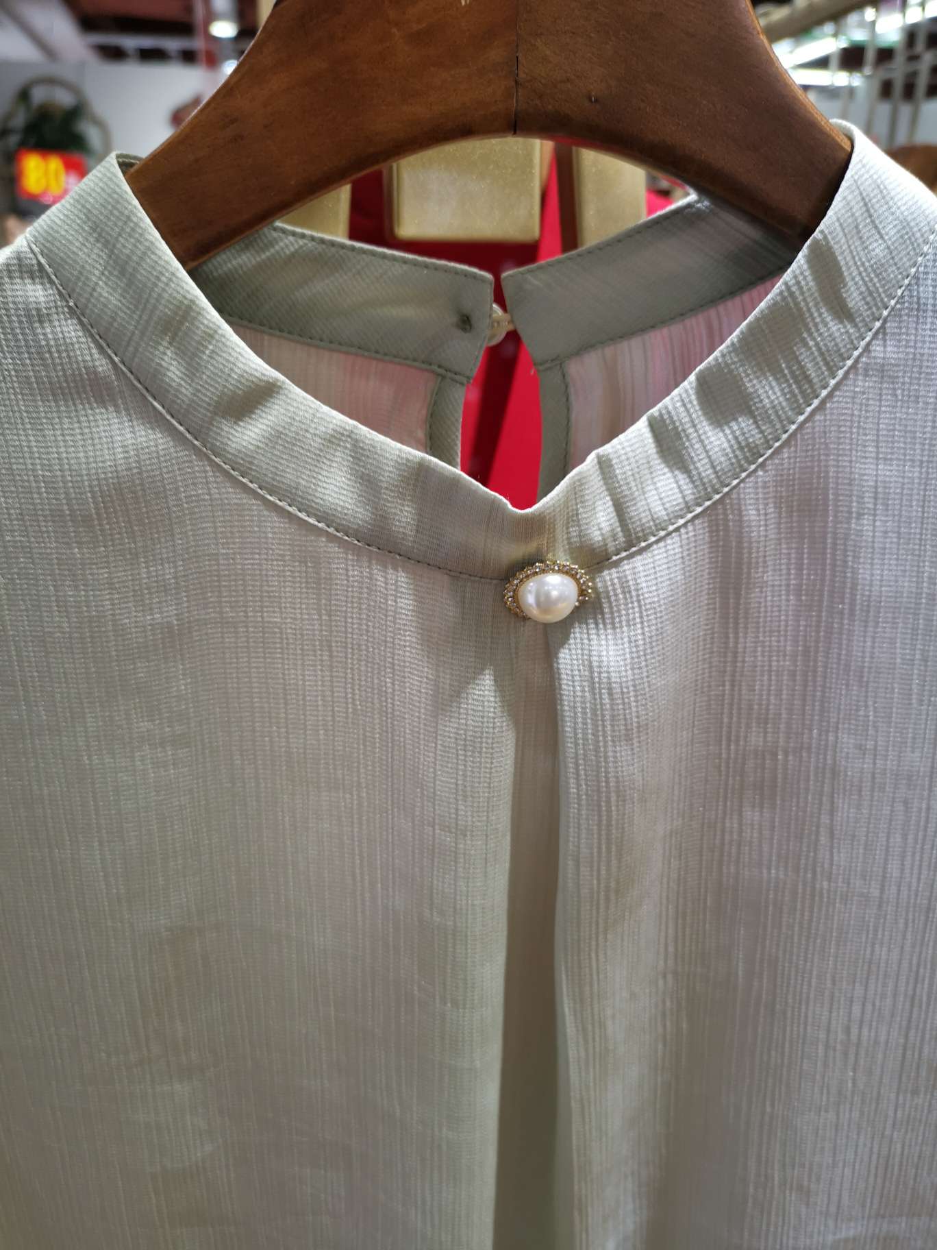 A fashionable women's top with a large pearl buckle collar details Picture