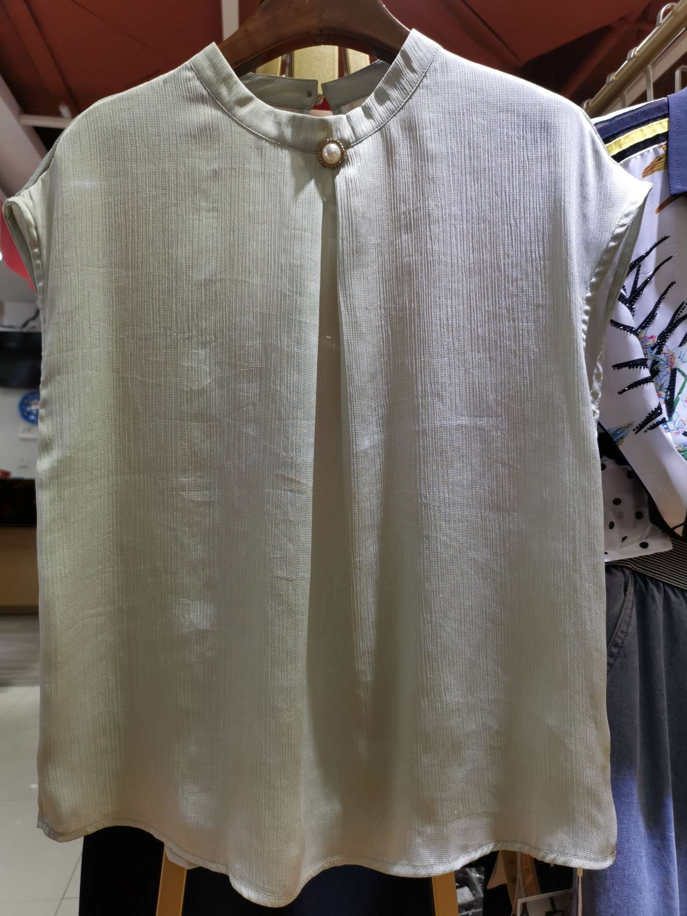 A fashionable women's top with a large pearl buckle collar