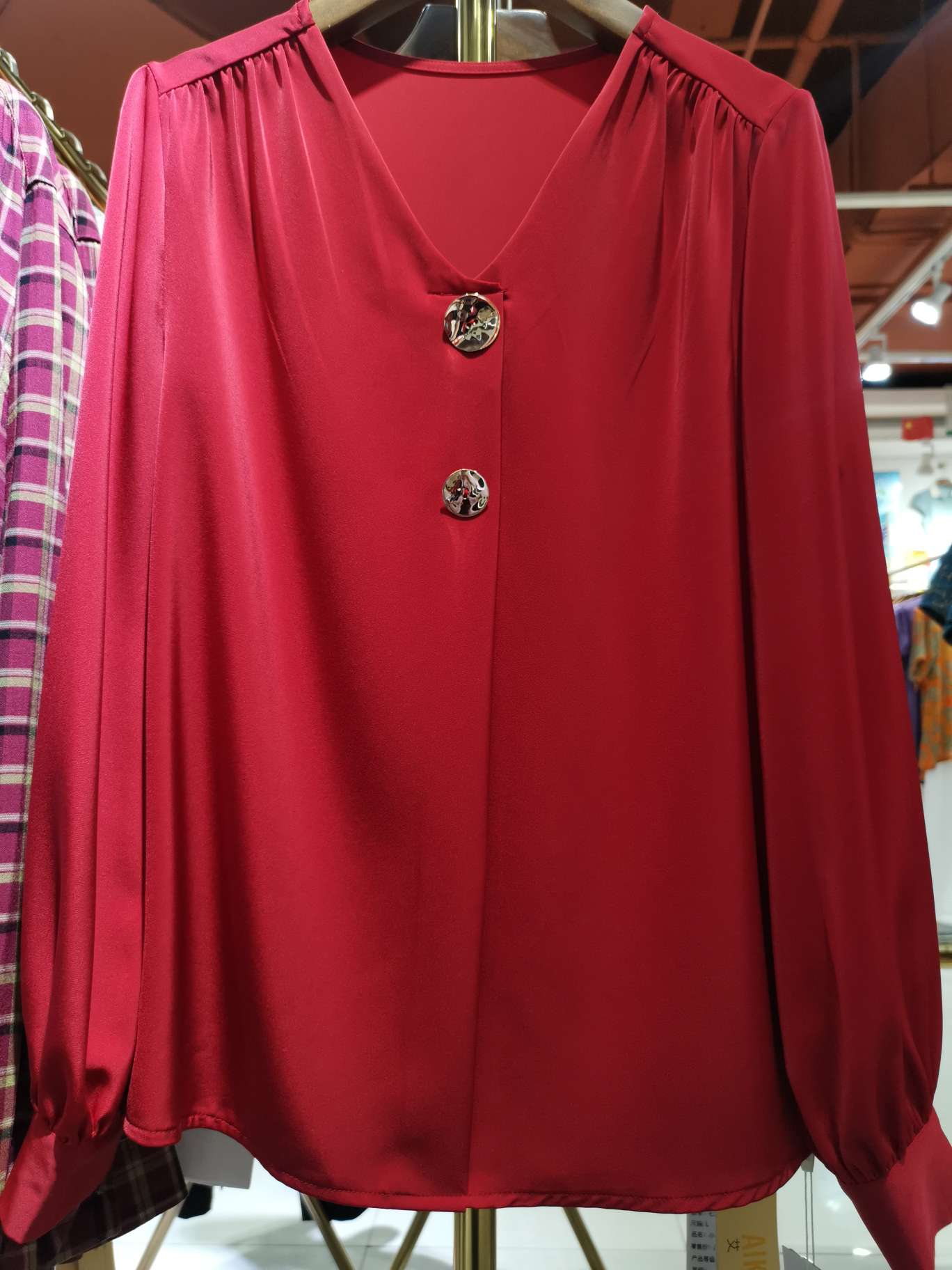 A fashionable long-sleeved women's top with a bright red V-neck and double buttons