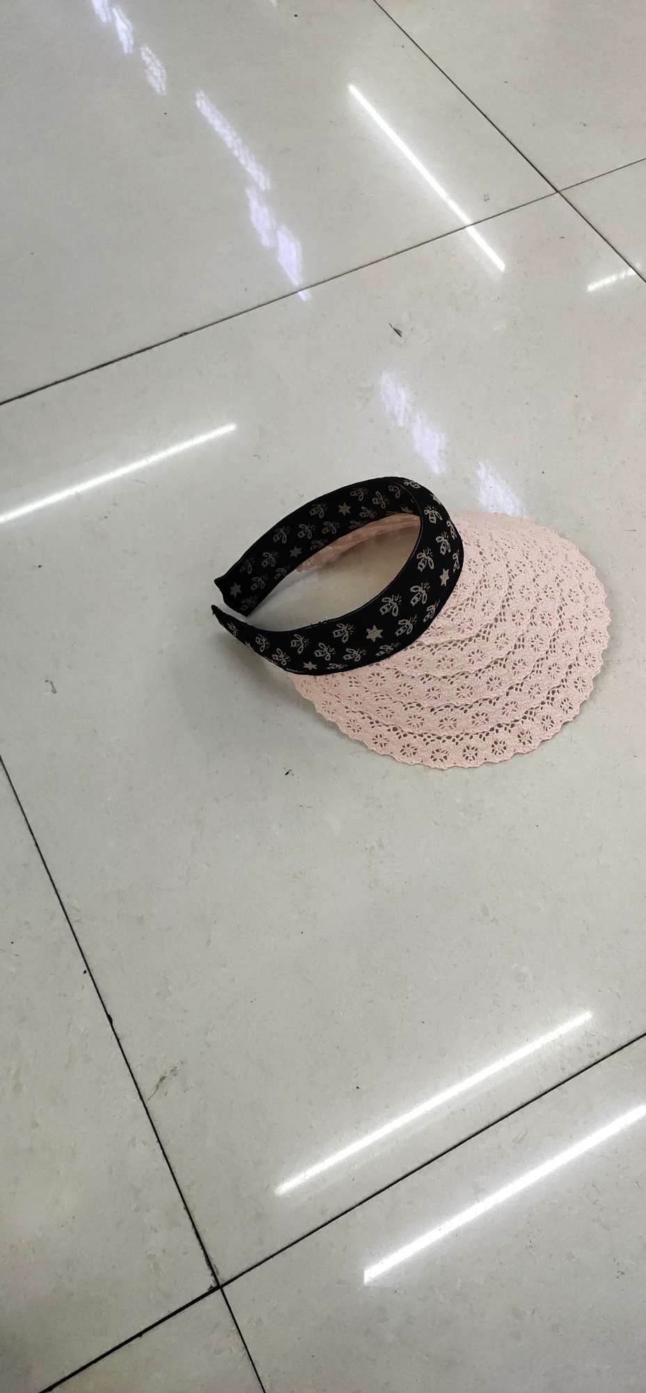 A lace sun hat with a straw hat on an empty top