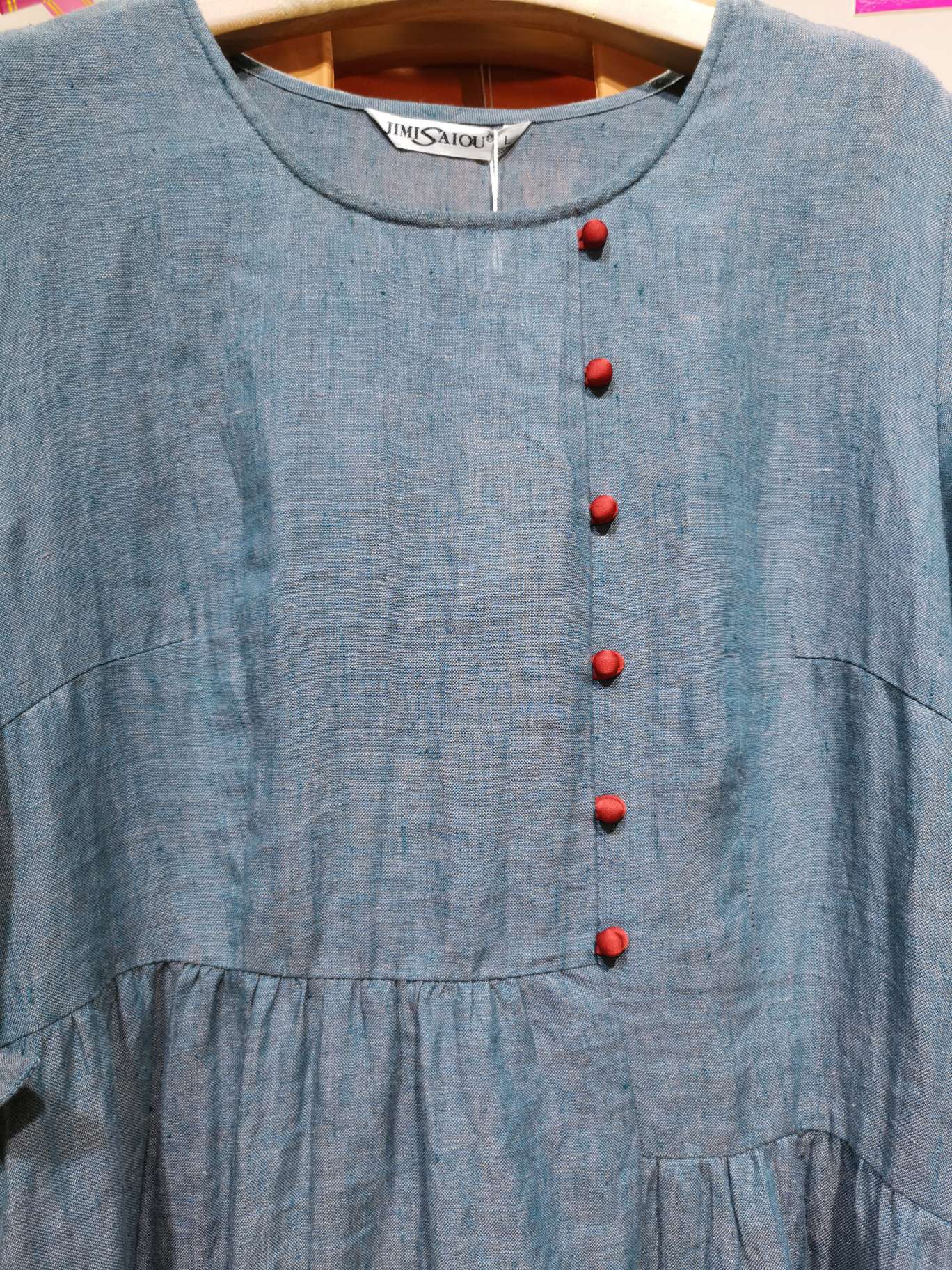 A fashionable long dress made of linen with a round neck and red buttons