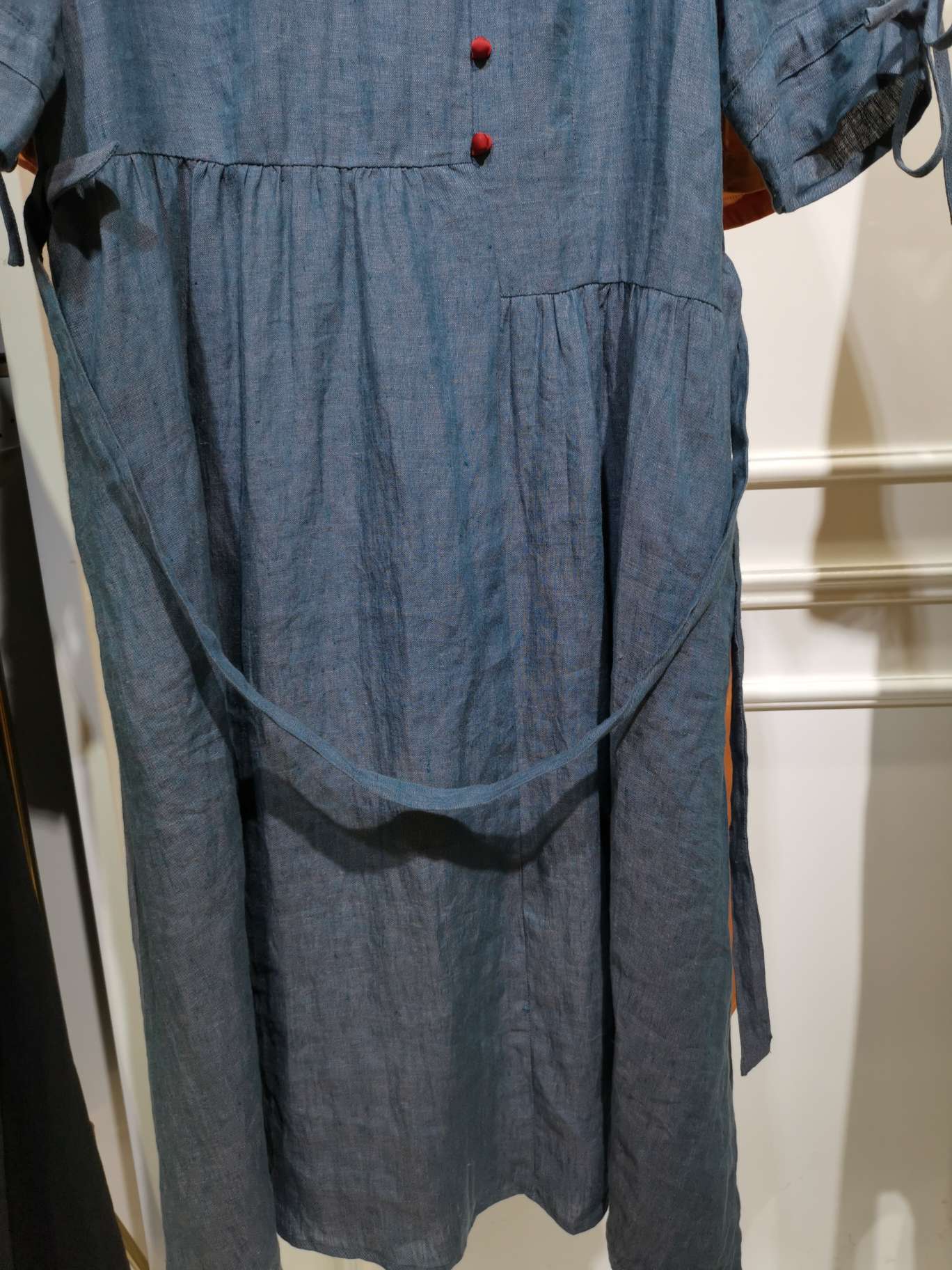 A fashionable long dress made of linen with a round neck and red buttons details Picture