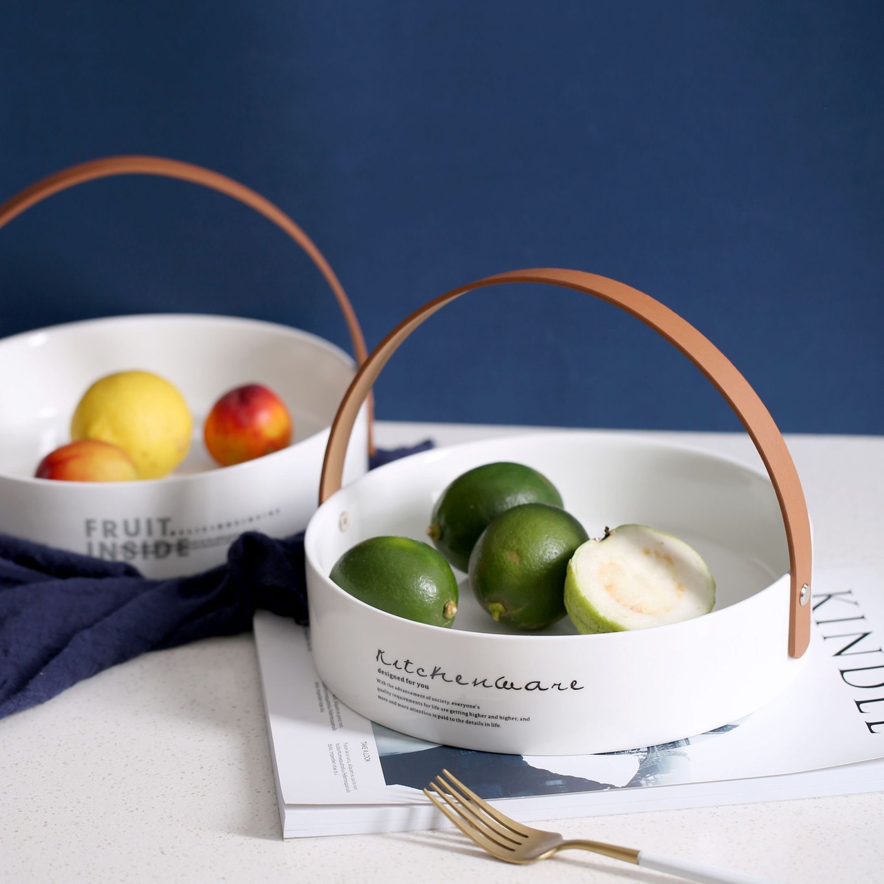 Ceramic and glass fruit basket on a wooden table with fresh oranges and grapes