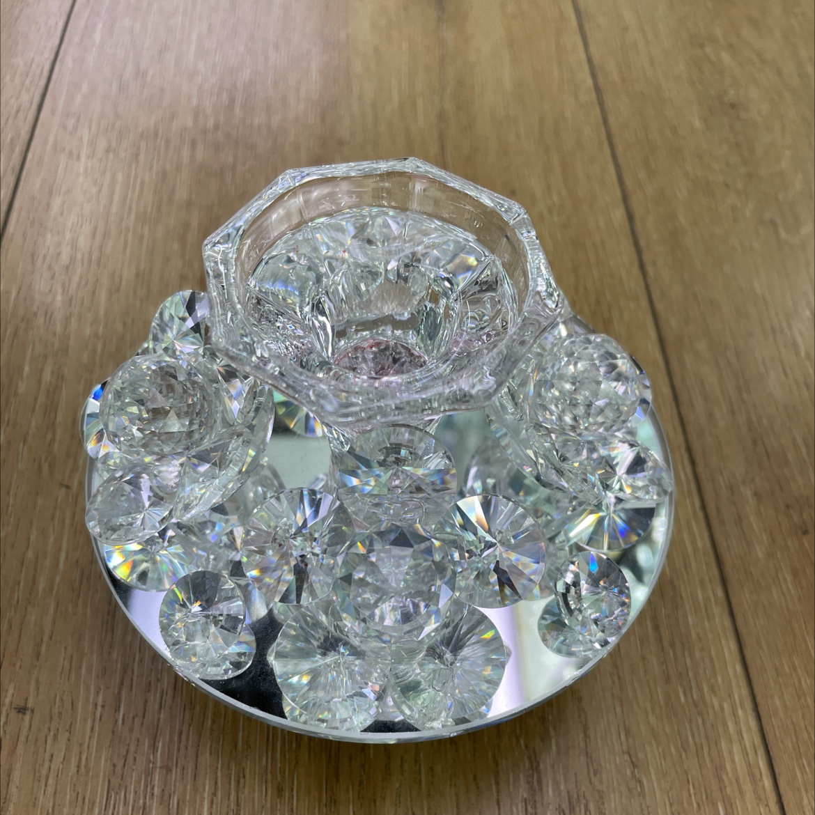 The glass handicraft, a glass candlestick head ornament, has a base, four flowers and four small diamonds, with a candlestick head in the middle. The whole piece is transparent