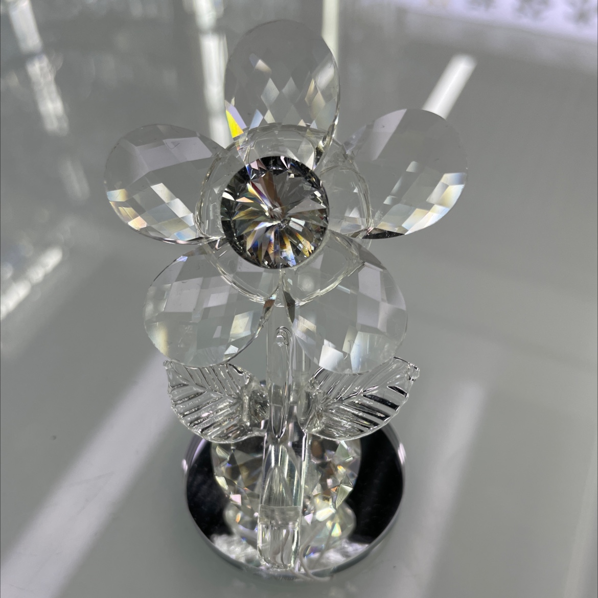 The glass flower ornament is overall transparent with a silver diamond in the center of the flower. It has a base and is very exquisite. It is a very beautiful glass handicraft
