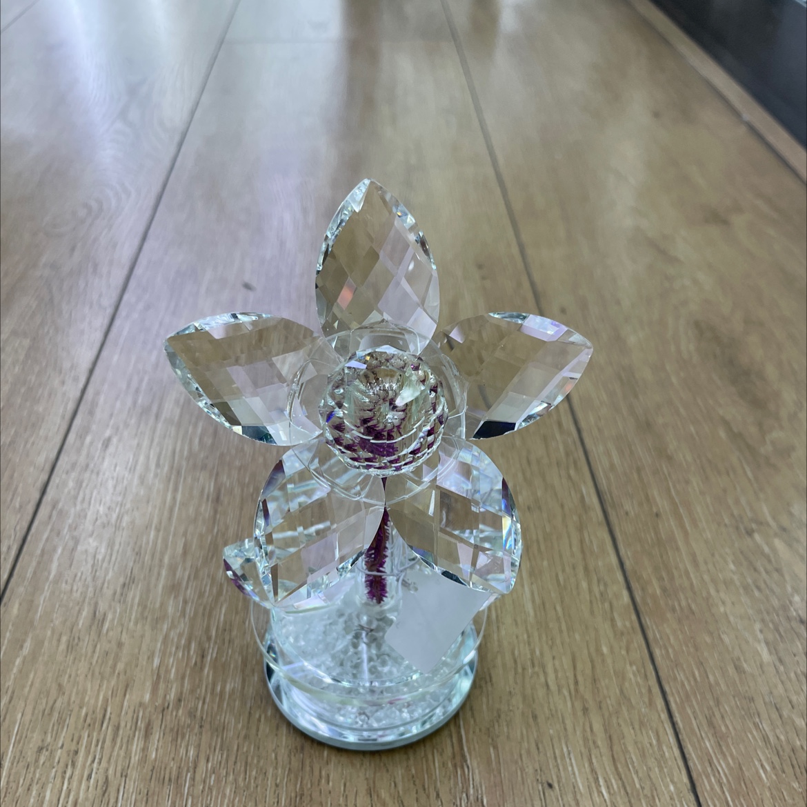 Glass flower ornament: A large flower with transparent stamens and petals. Five petals with a base. Inside the base, there are small diamonds. It has a light that will illuminate and is battery-powered