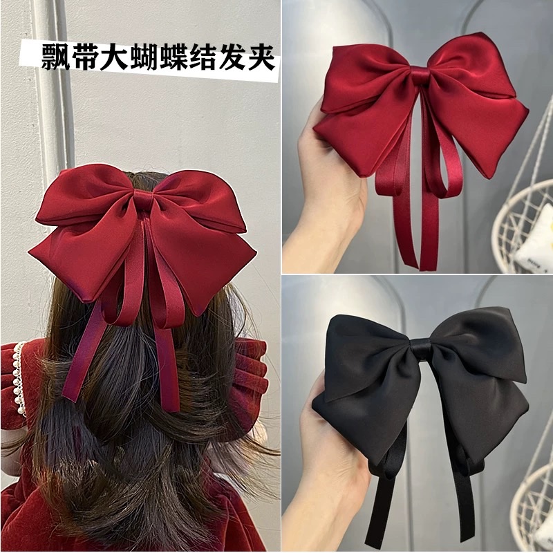 A large bow hairpin for children is stuck on the back of the head of a wine-red little girl princess for the New Year. A ribbon hairband is a cartoon hairband