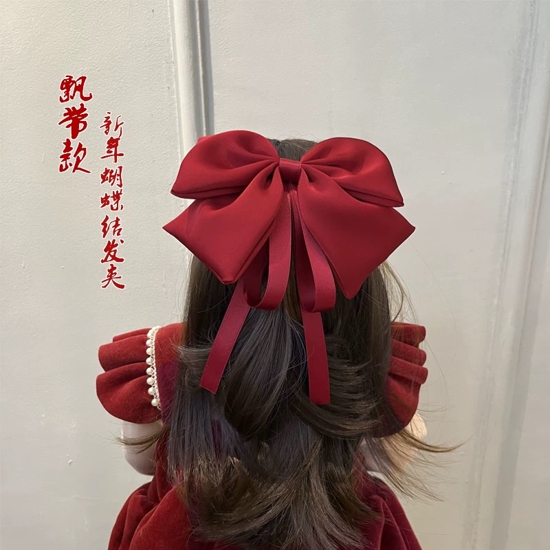 A large bow hairpin for children is stuck on the back of the head of a wine-red little girl princess for the New Year. A ribbon hairband is a cartoon hairband details Picture