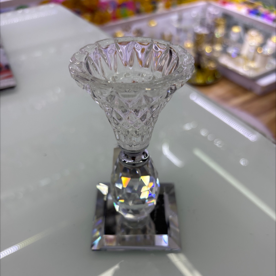 这是一个水晶烛台摆件，属于水晶工艺品。它采用透明水晶材质，通过精细的切割工艺呈现出丰富的棱面，光线照射下璀璨夺目。此类烛产品图