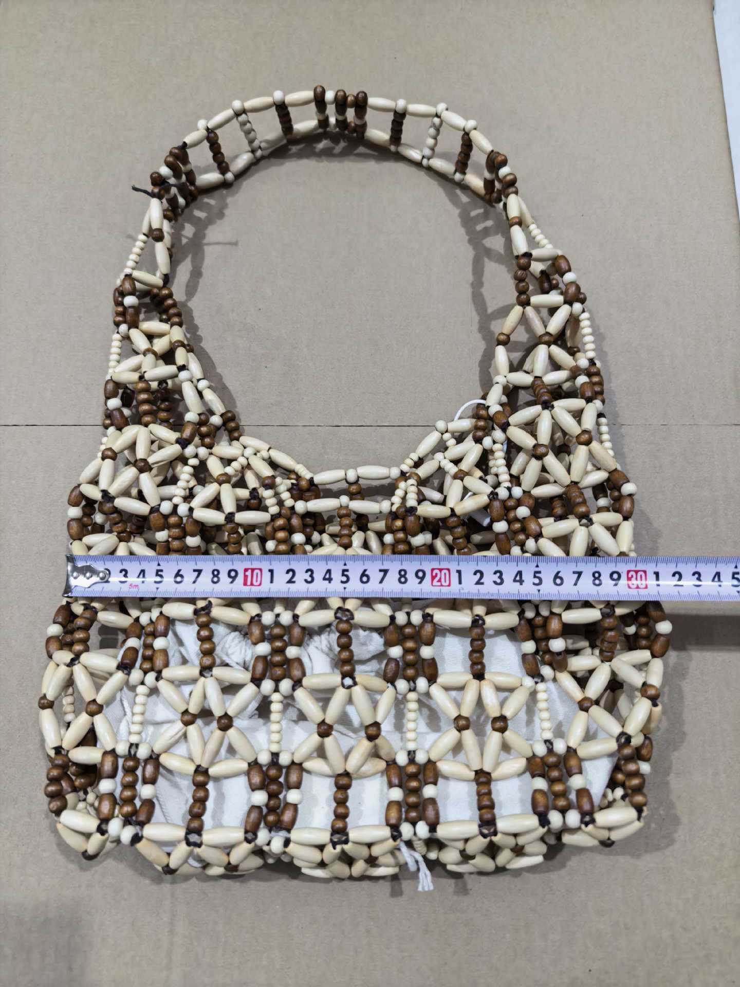 A new style of casual and versatile wooden beaded bag with a color-blocking and hollowed-out woven vacation beach bag and handcrafted beaded bag