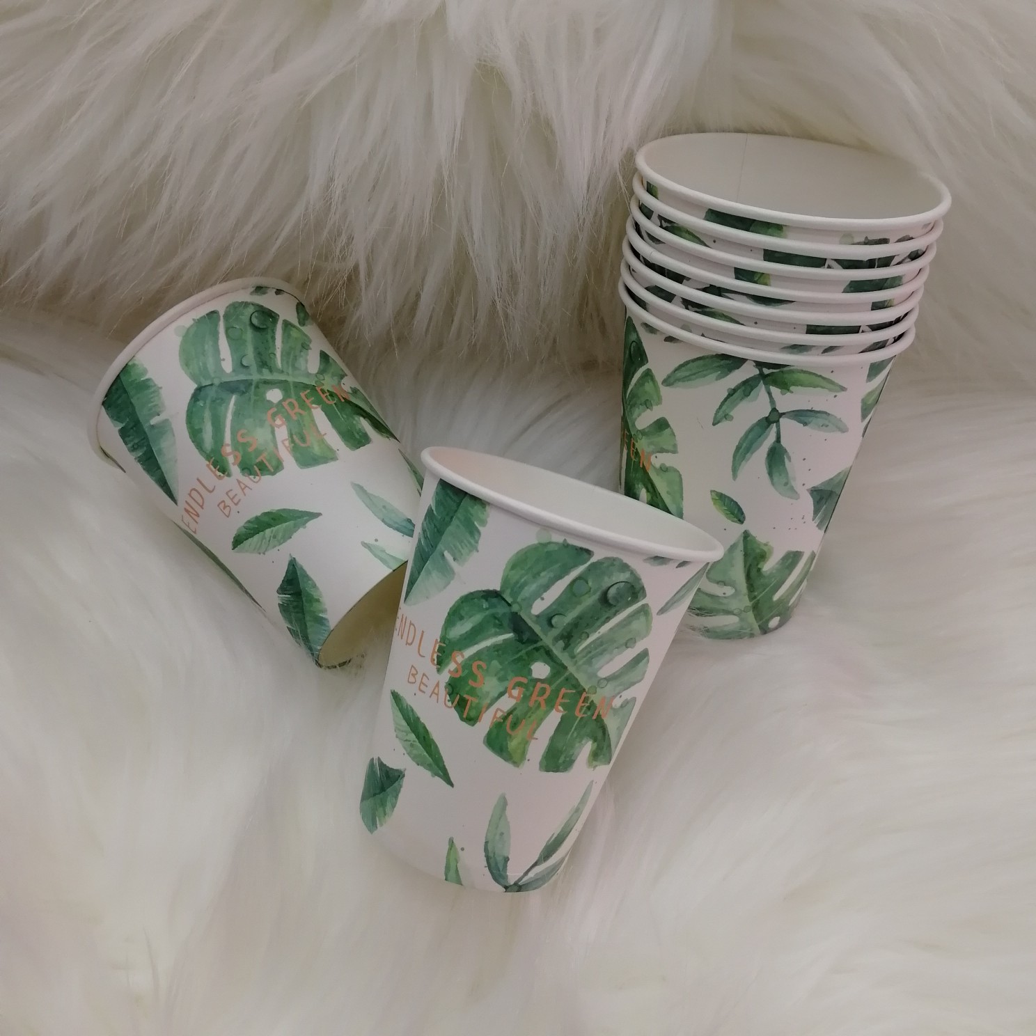 Paper cups arranged on a pastel-themed party table with cupcakes and flowers