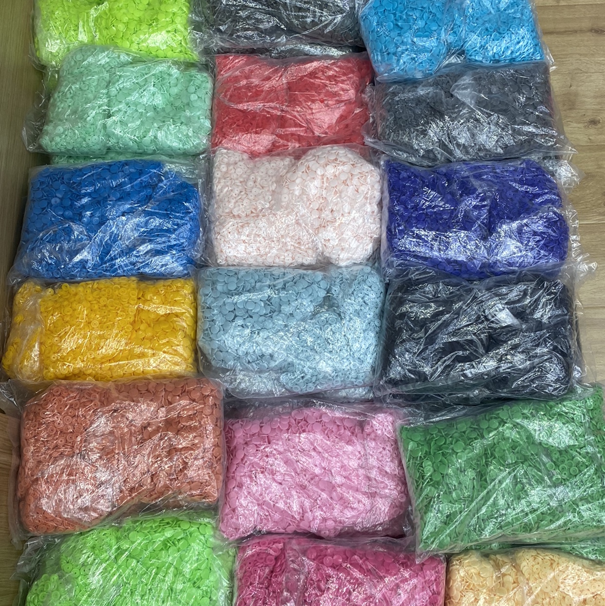 A large quantity of black, white and colored plastic T5 four-button snap fasteners, large white button raincoats, children's clothing and file bags in stock details Picture