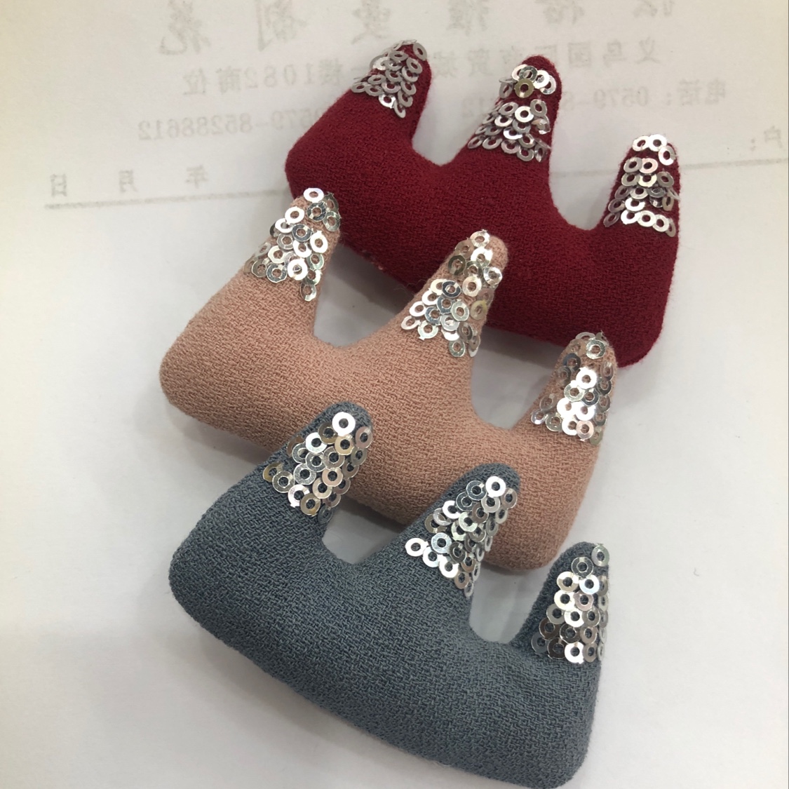 Embroidered sequins at the pointed corners of a linen crown thumbnail
