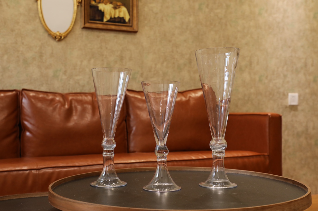 Tall glass cups are placed on a table for flower arrangement