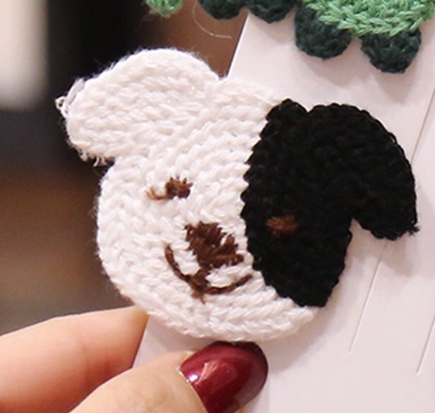 Close-up of fingers holding a crochet hook forming a rose-shaped yarn flower