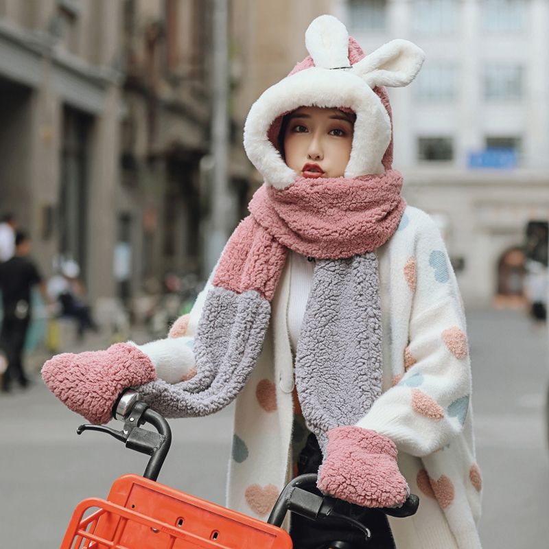 In winter, a sweet and cute Korean woman is wearing a three-piece hat, a scarf and a set of gloves