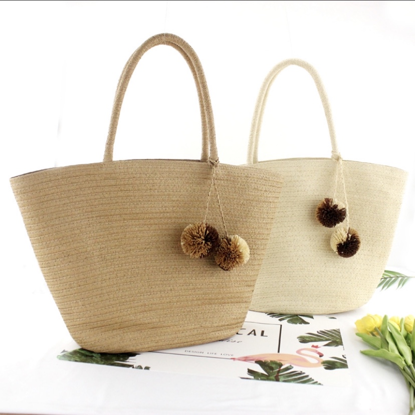 Casual women's bag made of straw and wide paper with hanging balls