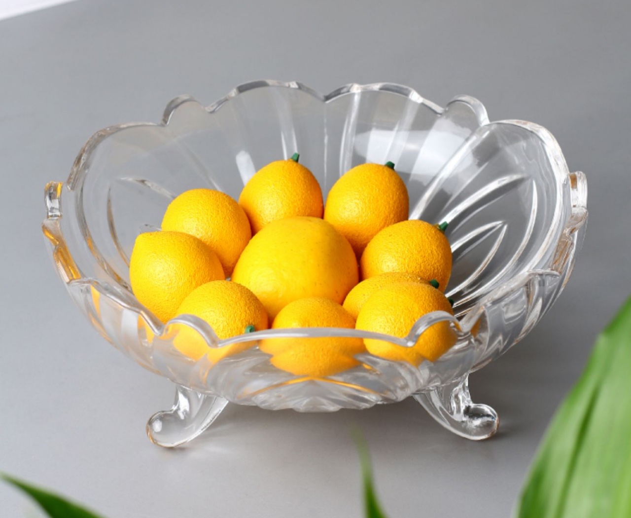 A three-legged fruit platter with a glass fruit bowl