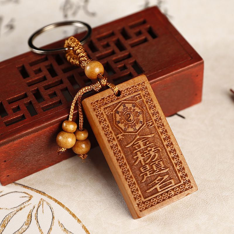 A flat keychain with engraved characters on peach wood, a symbol for achieving success in the imperial examination