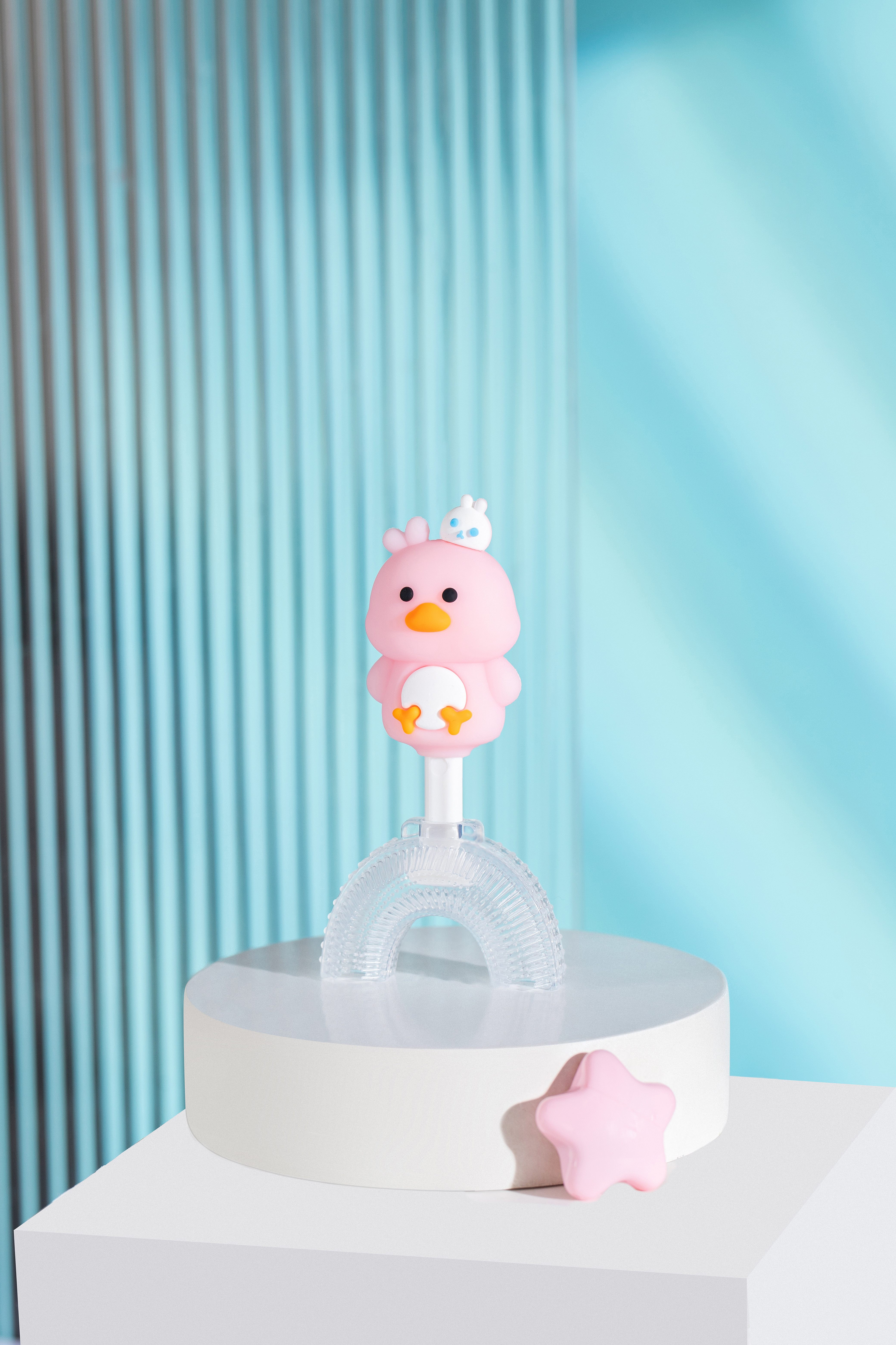 Child using U-shaped duck toothbrush with smiling parent