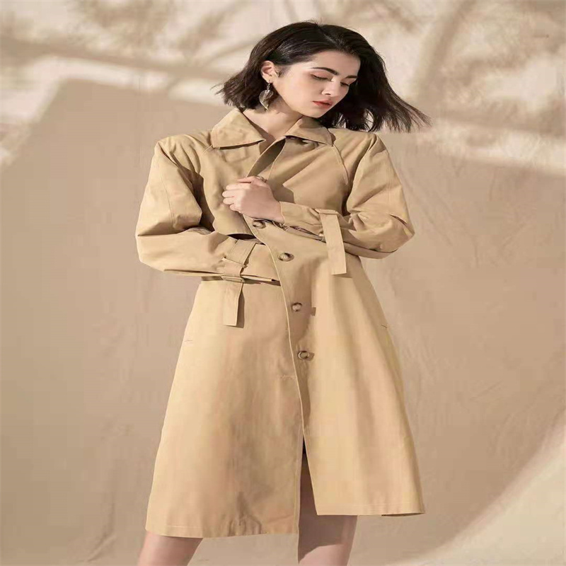 Trench coat in multiple colors laid out on a minimalist rack