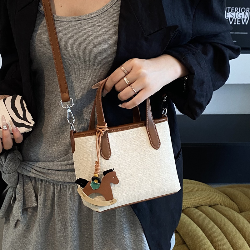 A simple and stylish hand-held bucket bag for women in the summer of 2025 with a Korean color scheme. It is a single-shoulder crossbody bag Application Scenario