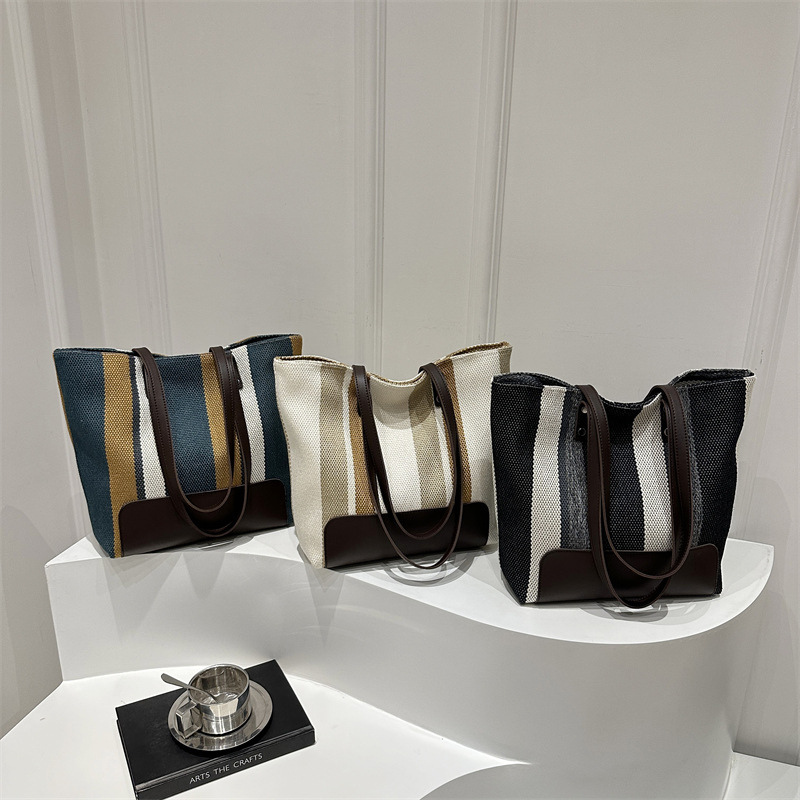 The new large-capacity commuting striped canvas bag and travel handbag of the casual single-shoulder tote bag for women in 2025 are selling well full figure