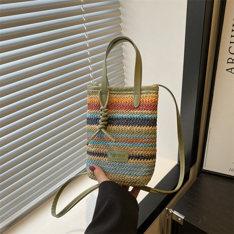 A new and niche design of a women's crossbody bag made of straw weaving in 2025, featuring color-blocking and patchwork ins woven hand-held small bag full figure
