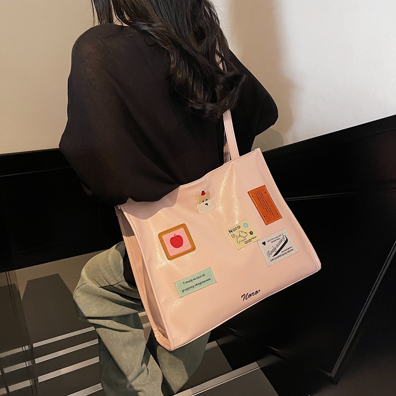 The 2025 new backpack is fashionable and versatile. The large-capacity tote bag is simple and cute for women. The cartoon sticker single-shoulder bag is trendy full figure