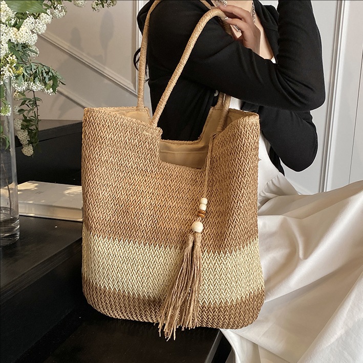 Seaside beach vacation straw woven bag for women 2025 New style hollowed-out color-blocked single-shoulder bag with tassels and large capacity bucket bag full figure