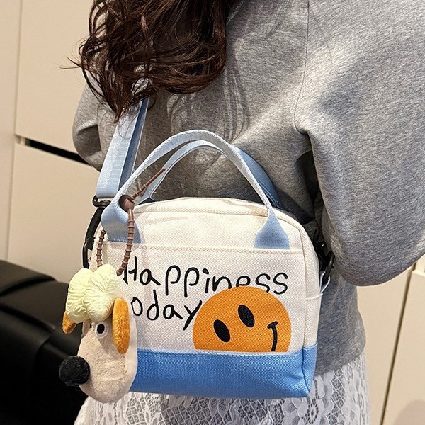 A cute smiling girl handbag carried out by hand, with a high level of appearance. A canvas bag with Korean-style prints and a trendy single-shoulder crossbody bag full figure