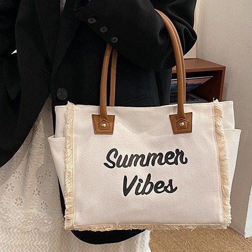The 2025 new Korean-style letter-fringed canvas bag for women, a large-capacity, simple commuting student single-shoulder tote bag full figure