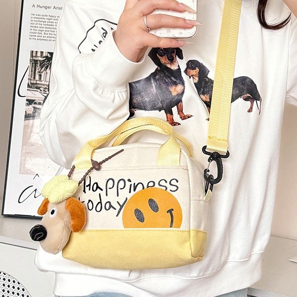 A cute smiling girl handbag carried out by hand, with a high level of appearance. A canvas bag with Korean-style prints and a trendy single-shoulder crossbody bag Application Scenario