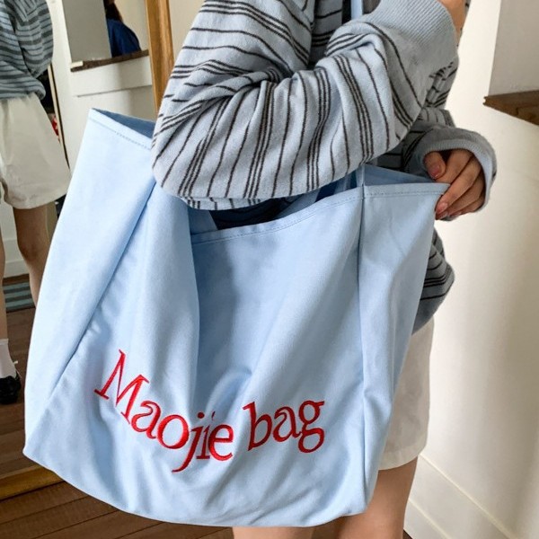The 2025 summer new letter niche design Korean-style canvas bag is a large-capacity commuting casual hand-held cloth bag for women full figure