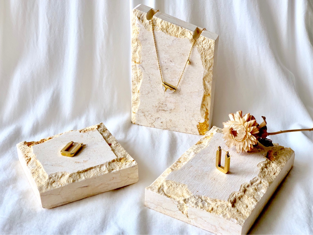 A natural stone and rock jewelry necklace display with a beige marble base for taking photos. Exhibition photo props full figure