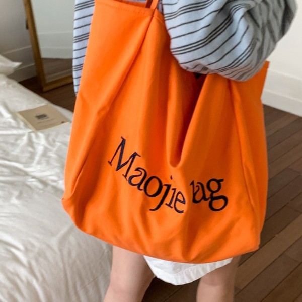 The 2025 summer new letter niche design Korean-style canvas bag is a large-capacity commuting casual hand-held cloth bag for women Application Scenario