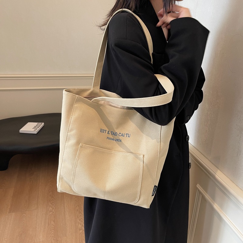 A simple and large-capacity canvas bag for women, a new model of 2025 for college students. It is a versatile single-shoulder tote bag for class and commuting to work full figure