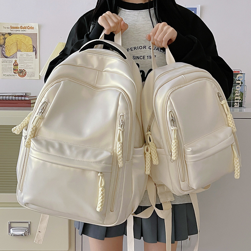 This is a simple and versatile commuter backpack in pearl color for girls. It has a Korean-style texture and is made of PU. It is a backpack for junior and senior high school students full figure