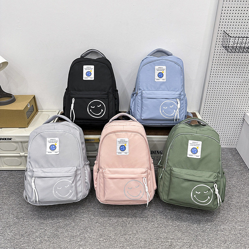 The 2024 new style of fashionable and simple backpacks for trendy boys and girls, large-capacity schoolbags for students, and cute smiling face printed backpacks full figure