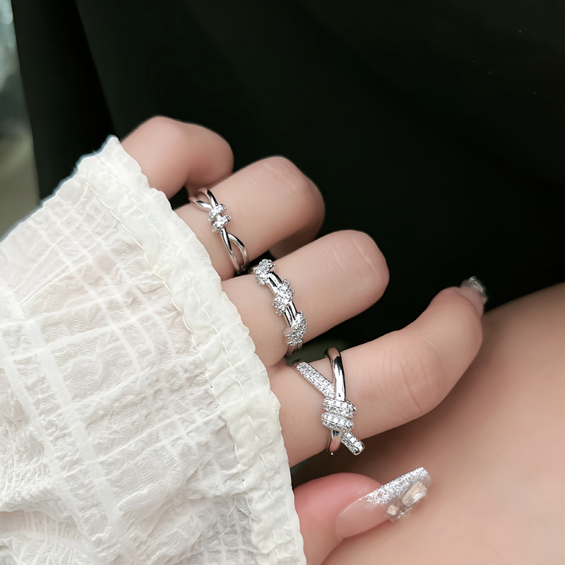 This is a fashionable and exquisite index finger ring with a unique design sense, slightly inlaid lines, and a simple opening. It features a crossed knot and a cold style full figure