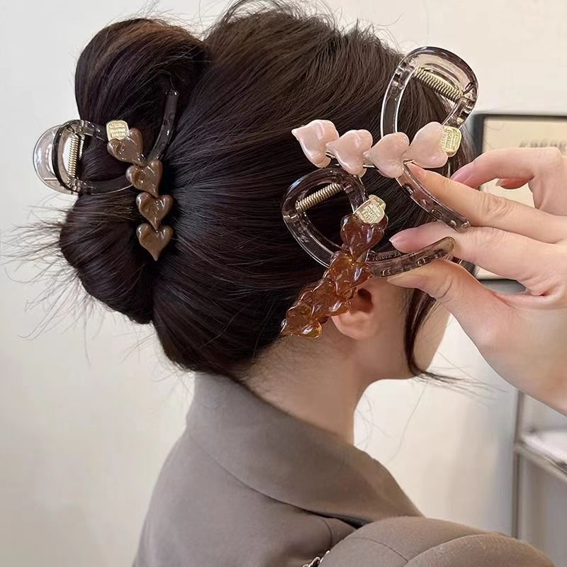The stylish and heart-shaped hair clip is a medium-sized, updo clip for the back of a woman's head. It exudes a sense of sophistication and is an ins minimalist shark clip hair clip full figure