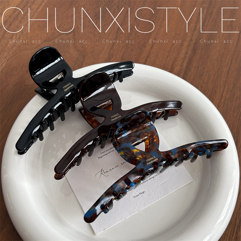 The large-sized acetate hair clip has a lot of volume and a retro style. It's a 13cm large-sized shark clip at the back of a woman's head full figure